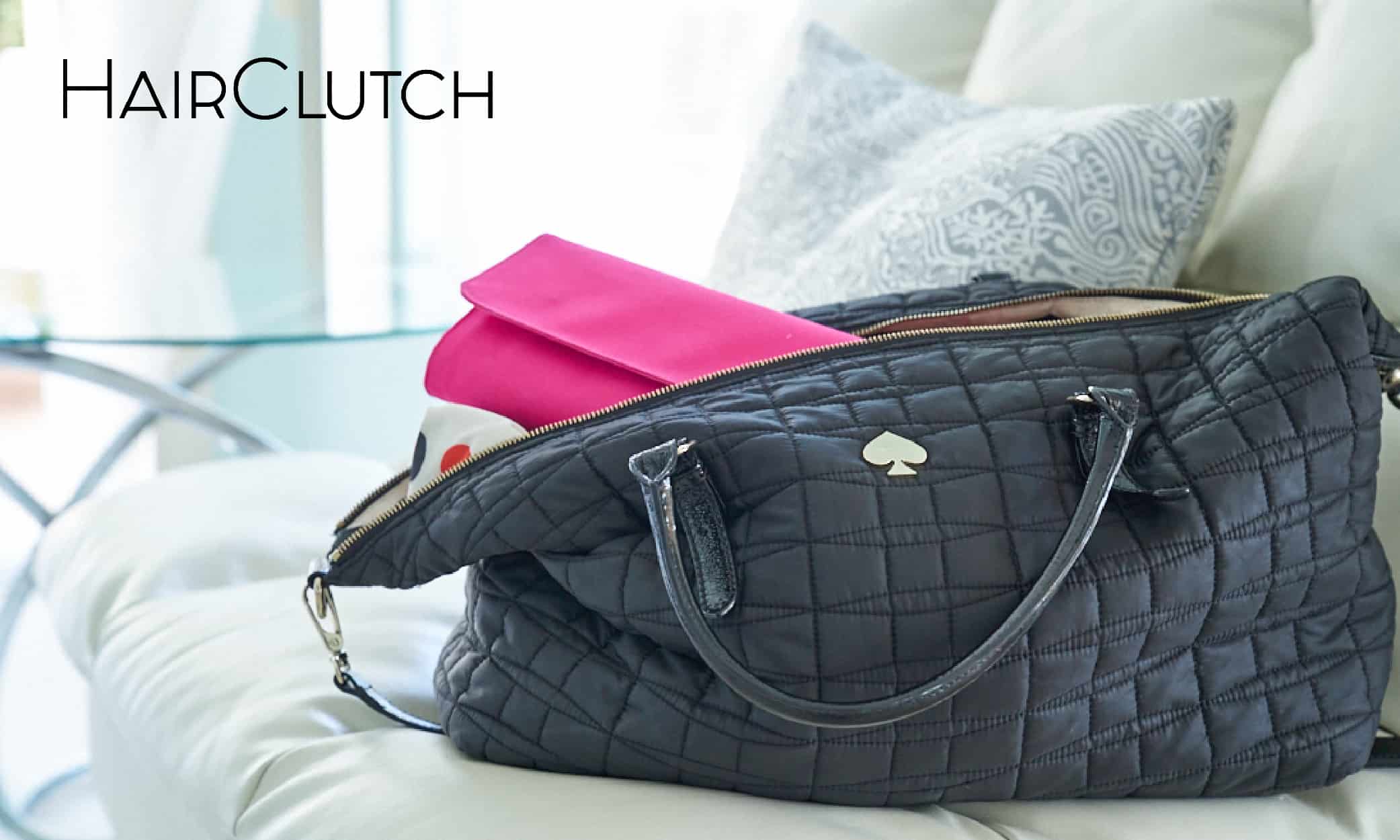 A black HairClutch purse back sitting on a couch